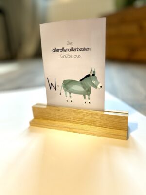 Einfacher handgearbeiteter Postkartenhalter aus Eichenholz mit bestückter Beispielkarte, die einen Esel abbildet